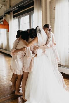 the bride and her bridals are hugging each other in front of a window