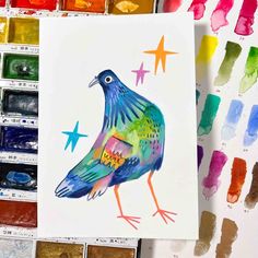 a bird painted on paper next to some watercolors