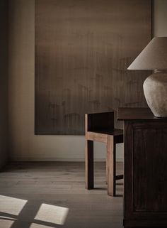 a lamp sitting on top of a wooden table next to a vase and small chair