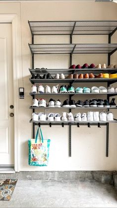 there are many pairs of shoes on the shelves next to the door in this room