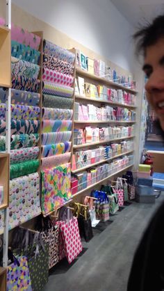 a man standing in front of a store filled with lots of colorful bags and gifts