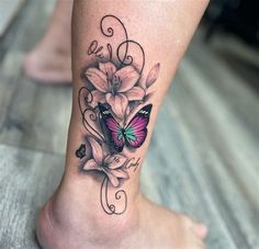 a woman's foot with a butterfly and flowers tattoo on the side of her leg