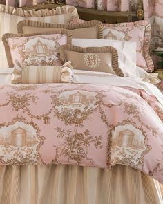 a bed with pink comforter and pillows on top of it