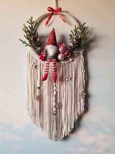 a christmas decoration hanging on the wall with red and white decorations, pine cones, ornaments and bells