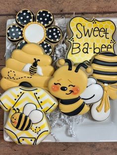 decorated cookies in the shape of bees and honeybees on a plate with words sweet ba - bee