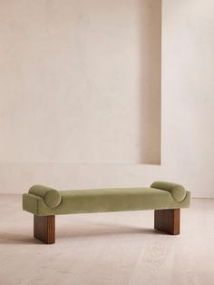 a green bench sitting on top of a hard wood floor next to a white wall