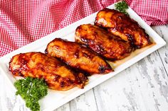 two pieces of chicken on a white plate with parsley and red checkered tablecloth