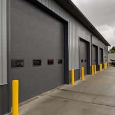 an empty parking lot next to two garages with yellow and gray poles on each side