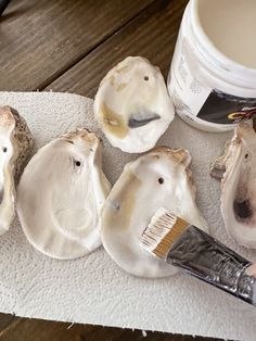 a person is painting some white mushrooms on the table next to a paint can and brush