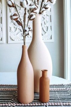 three vases sitting on top of a table with cotton flowers in them and one is empty