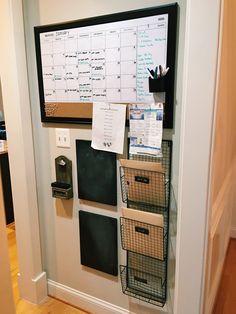 a bulletin board with several baskets on it in the corner next to a wall mounted dry eraser