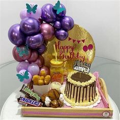 a birthday cake with balloons and sweets on a table in front of a plate that says happy birthday