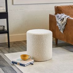 a chair and ottoman in a living room with a coffee cup on the floor next to it