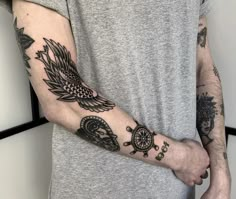 a man's arm with tattoos on it and an eagle, wheel, compass