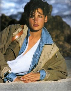 a young man sitting on the ground wearing a jacket