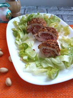 a white plate topped with lettuce and meat on top of a bed of lettuce