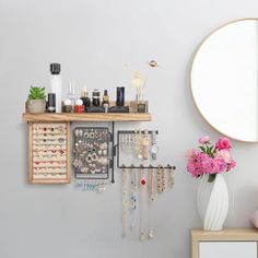 there is a mirror, vase with flowers and jewelry on the shelf next to it