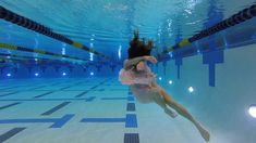 a woman in a white dress is diving into a swimming pool with her arms outstretched