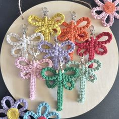 several crocheted key chains are arranged on a white plate with flowers in the background