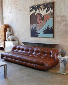 a brown leather couch sitting in front of a painting