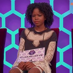 a young woman sitting in a chair with her name tag on it's chest