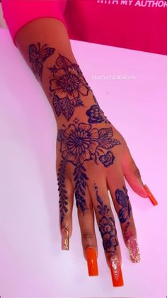 a woman's hand with henna tattoos and orange nail polishes on it