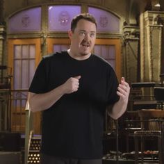 a man standing in front of a microphone and giving a thumbs up while wearing a black t - shirt