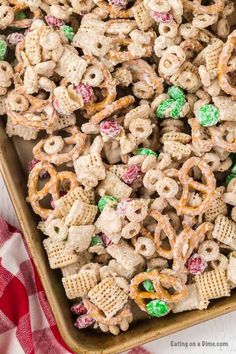 a tray filled with cereal and pretzels next to a red checkered table cloth