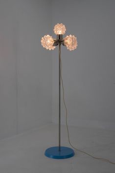 a floor lamp that is on top of a blue base and has three lights attached to it