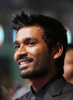 a man in a suit and tie smiles at the camera while looking off into the distance