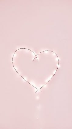 a heart - shaped string with lights hanging from it's sides on a pink background