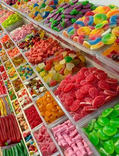 many different colored candies are on display in bins with dividers to the sides