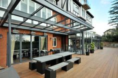 an outdoor dining area with benches and tables on a wooden deck next to a building