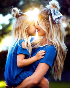 a mother and daughter hugging each other in the park with sunlight shining through trees behind them