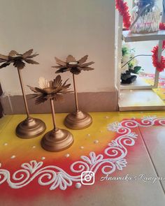 three small metal flowers on top of a yellow and red floor next to a window