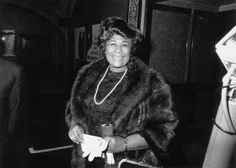 an old black and white photo of a woman in a fur coat smiling at the camera