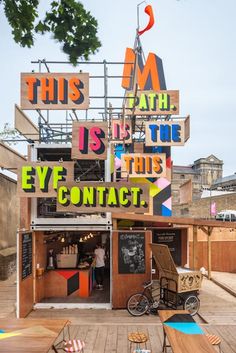 an outdoor cafe with lots of signs on the roof and tables in front of it