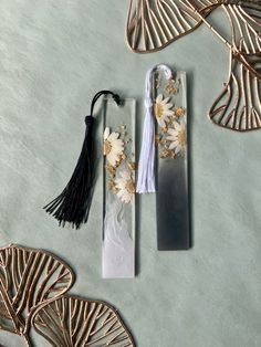 two bookmarks with flowers and tassels on them sitting next to each other