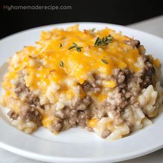 a white plate topped with macaroni and cheese covered in ground beef on top of mashed potatoes