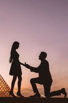 a man kneeling down to shake hands with a woman in front of the eiffel tower