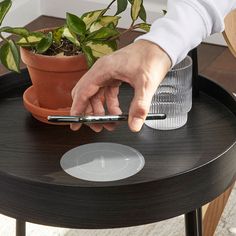 a person using a cell phone on top of a table next to a potted plant