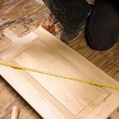 a person measuring the width of a piece of wood with a tape measure on it