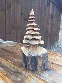 a small tree made out of logs on a wooden table in front of a fence