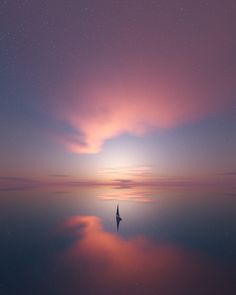 a lone sailboat is silhouetted against the night sky as it sits on calm water