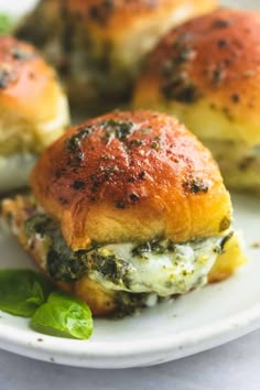 small sandwiches with spinach and cheese on a white plate