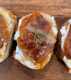 three pieces of bread topped with jelly and cream on top of a wooden cutting board