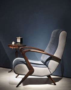 a chair sitting on top of a white floor next to a table with a clock