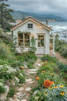 a small white house sitting on top of a lush green hillside next to the ocean