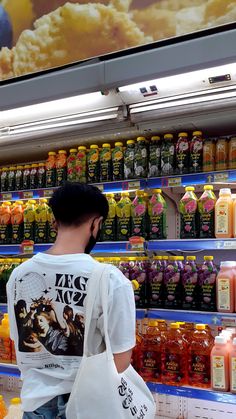 a man standing in front of a shelf filled with drinks and juices at a grocery store