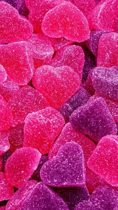 pink and red heart shaped candies are in the middle of purple and red candy